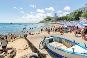 Una playa con una hilera de barcos, una bicicleta y gente disfrutando del agua.