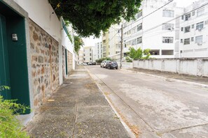 Eine schmale Stadtstraße mit Wohnhäusern, parkenden Autos und einem Bürgersteig.