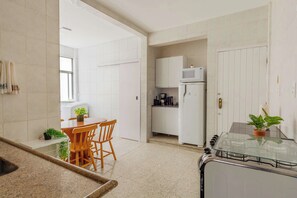 Eine moderne Küche mit weißen Schränken, einem Esstisch mit Stühlen und einem Kühlschrank.