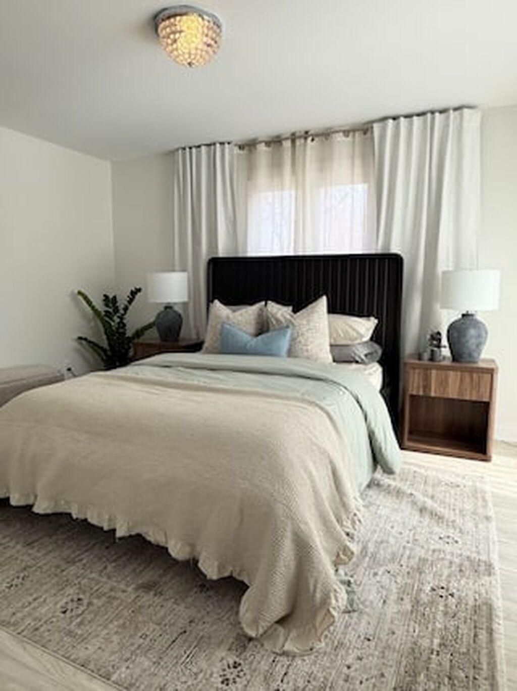 A bedroom with a bed, nightstands, a lamp, and a ceiling light fixture.