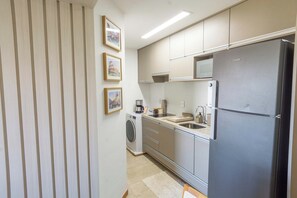 A compact kitchen with a built-in washer, a refrigerator, and a microwave. - 2BR at Corsário Beach | Pool & A/C (Salvador)