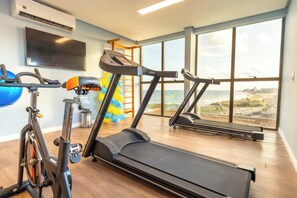 Ein Fitnessraum mit einem Ergometer, Crosstrainer, Laufband und einer Klimmzugstange.