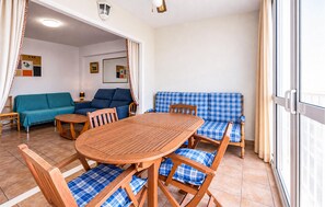 Una habitación con una mesa y sillas de madera, un sofá azul y un banco azul a cuadros.