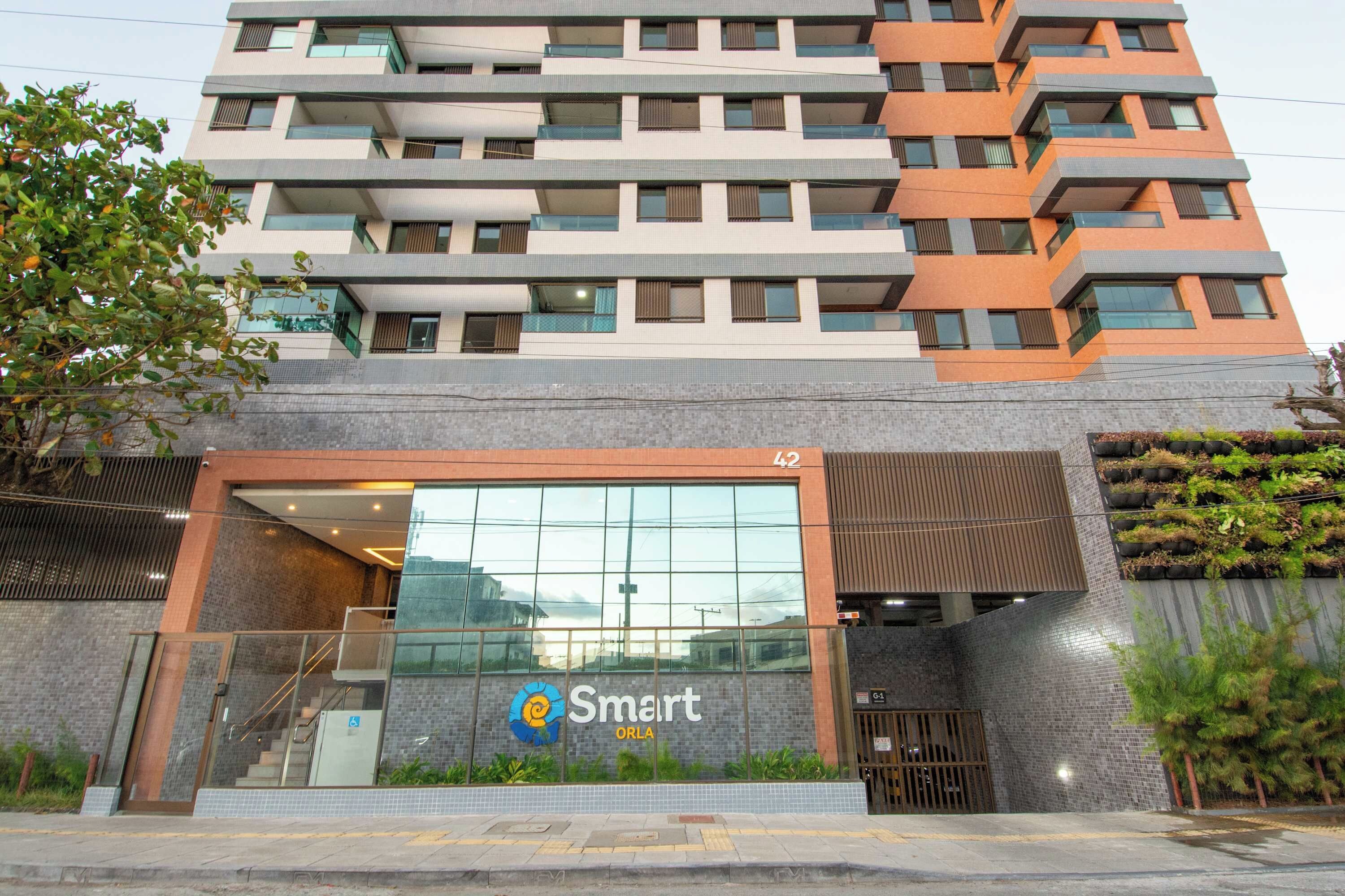 Un edificio moderno con entrada de vidrio, un logotipo con un remolino azul y amarillo, y el nombre 'Smart ORLA' en la fachada.