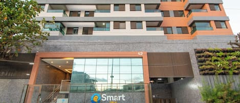 Un edificio moderno con entrada de vidrio, un logotipo con un remolino azul y amarillo, y el nombre 'Smart ORLA' en la fachada.