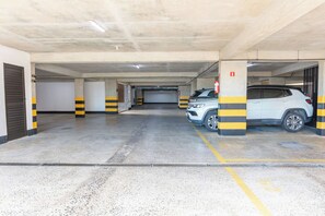 A multi-level parking garage with concrete floors and yellow-striped pillars. - Ocean View at Corsário Beach | Pool & A/C (Salvador)