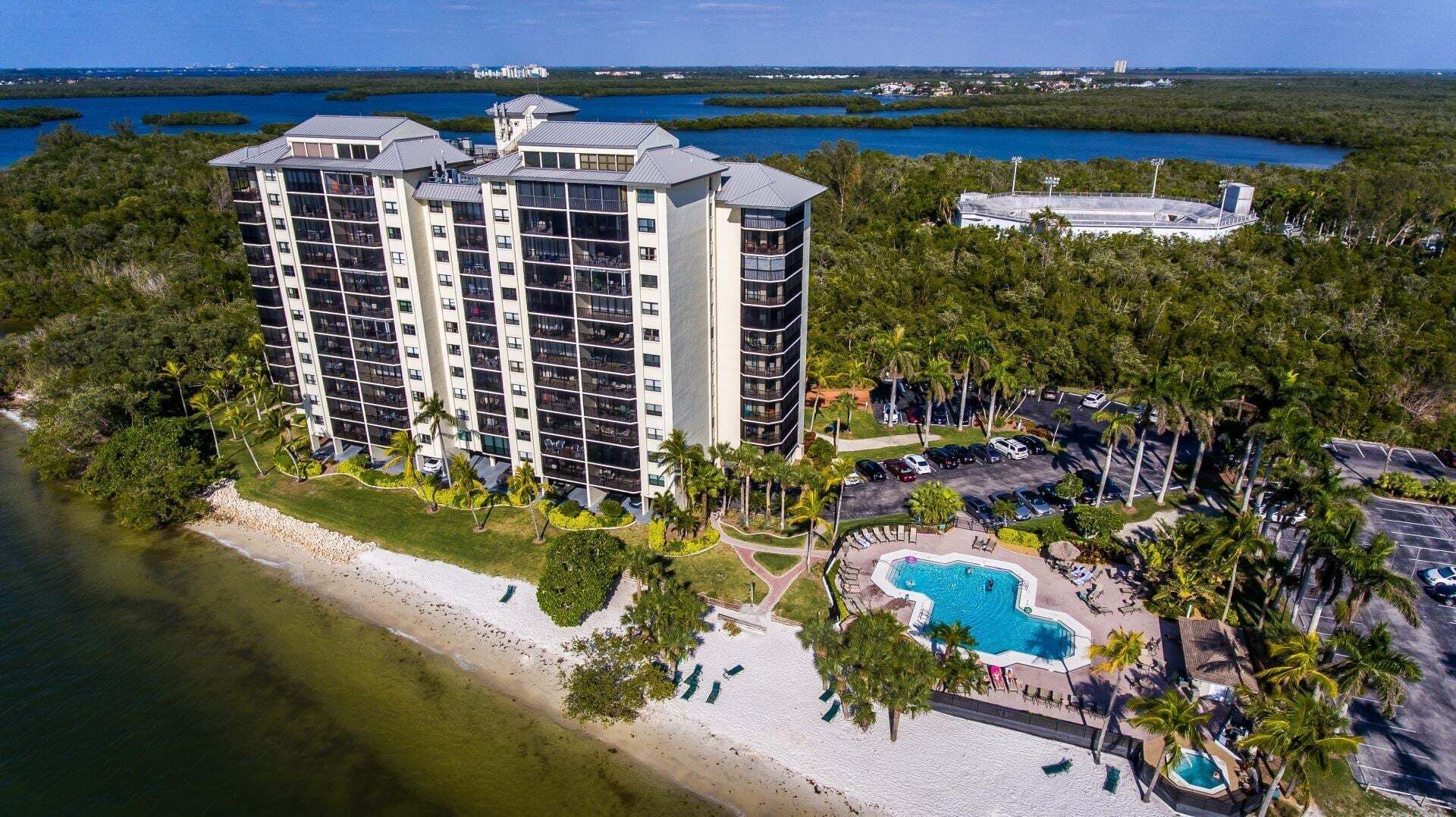 Un grand hôtel avec de nombreux étages, situé en bord de mer et doté d’une piscine.