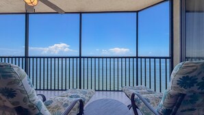 Ein Balkon mit Meerblick, ausgestattet mit zwei Stühlen und einem kleinen Tisch.
