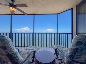 A balcony with a view of the sea, equipped with two chairs and a small table. - Sanibel Harbour Resort -Harbour Tower 913: Enjoy the most spectacular waterfront sunsets. (Fort Myers)