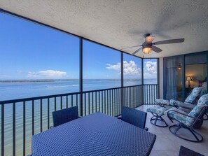 A balcony with a view of the ocean, a ceiling fan, and outdoor furniture. - Sanibel Harbour Resort -Harbour Tower 913: Enjoy the most spectacular waterfront sunsets. (Fort Myers)