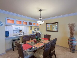 A dining area with a glass-top table, wicker chairs, and a vase with branches. - Sanibel Harbour Resort -Harbour Tower 913: Enjoy the most spectacular waterfront sunsets. (Fort Myers)