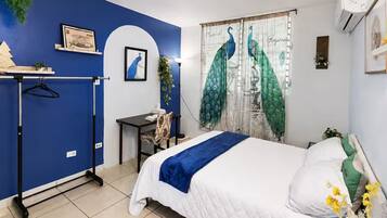 Une chambre à coucher comprenant un lit, un bureau, une chaise, une armoire et une fenêtre avec des rideaux.