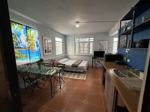 A compact living space with a dining area, a bed, a TV, and a kitchen area.