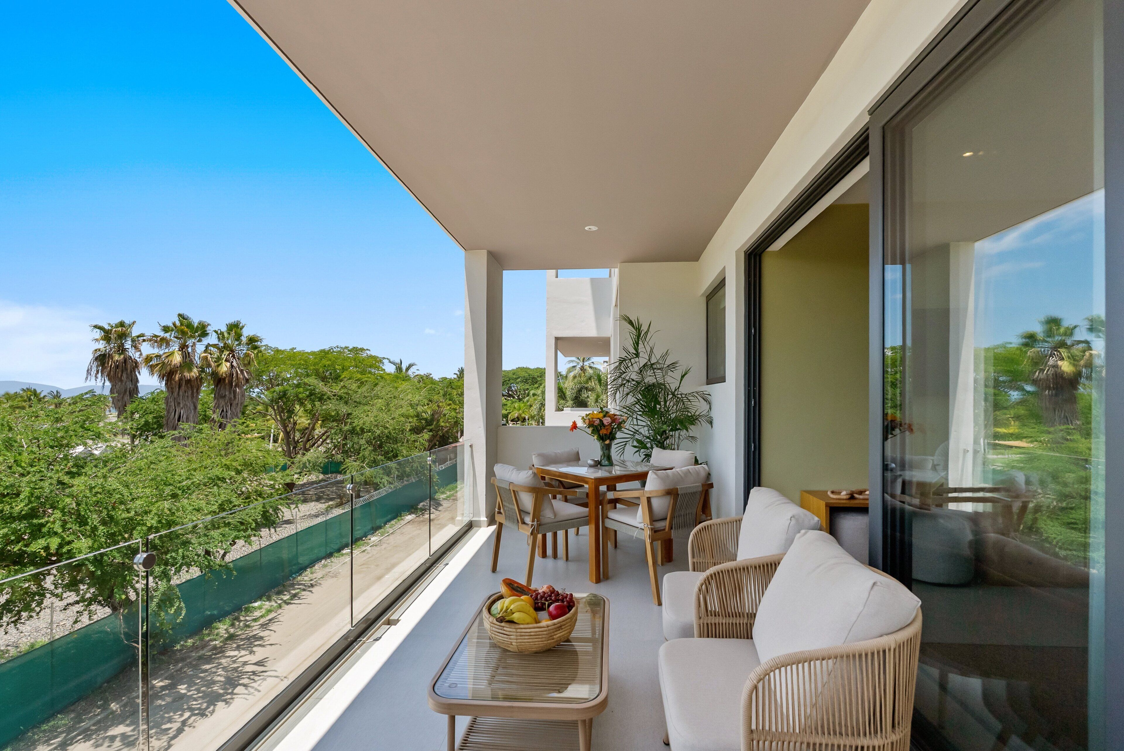 A balcony with a table, chairs, and a fruit bowl.