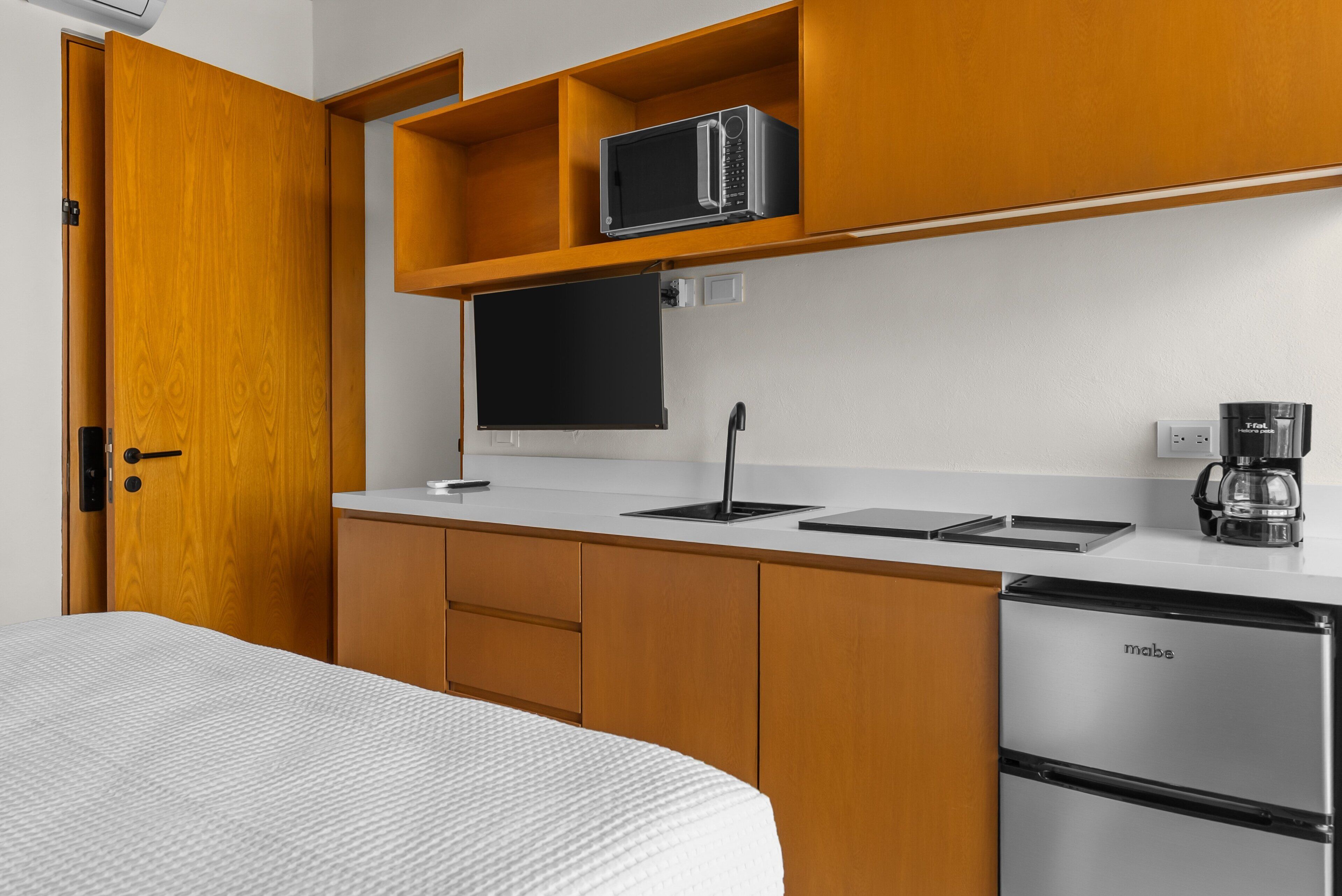 A compact kitchenette with a microwave, coffee maker, and a refrigerator.