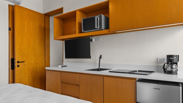Una piccola cucina accessoriata con forno a microonde, macchina del caffè e frigorifero.
