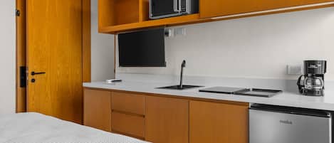 A compact kitchenette with a microwave, coffee maker, and a refrigerator.