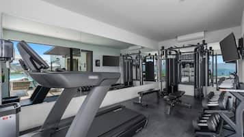 Un gimnasio moderno con una cinta de correr, máquinas de pesas y una banca.