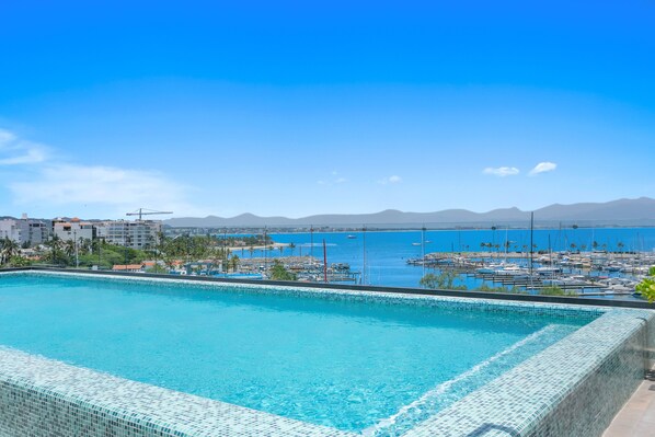 A swimming pool with a view of a marina and distant mountains.