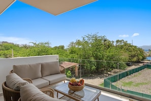 Ein Balkon mit einer Couch und einem Tisch mit Obstschale.