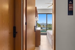 Habitación de hotel con vista a la playa y las montañas, un balcón y un diseño moderno.