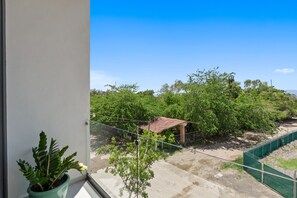 A view from a window overlooking a green landscape with trees and a small structure. - Marina View Condo w/ Rooftop Pool, Gym & Beach Club – La Cruz, sleeps 6 (Bahia de Banderas)