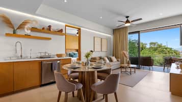 A modern kitchen with a dining area, a built-in oven, and a large window offering a view of greenery.