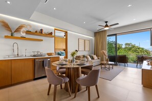 A modern kitchen with a dining area, a built-in oven, and a large window offering a view of greenery. - Marina View Condo w/ Rooftop Pool, Gym & Beach Club – La Cruz, sleeps 6 (Bahia de Banderas)