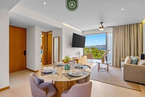 Ein modernes Wohnzimmer mit Flachbildfernseher, Essbereich mit Tisch für Zwei und einer Couch.