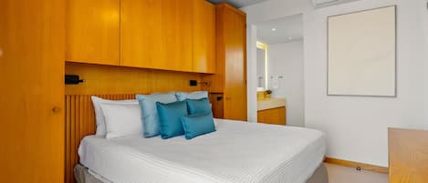 Quarto com cama, cabeceira de madeira, ventilador de teto e ar condicionado.