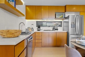 A modern kitchen with wooden cabinets, a stainless steel refrigerator, and a built-in microwave. - 2BR, 2BA Alik A5 condo in La Cruz with pool, gym, balcony, AC, WiFi. (Bahia de Banderas)