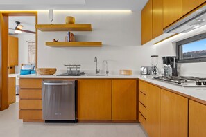 A modern kitchen with wooden cabinets, a stainless steel dishwasher, and a gas stove. - Modern 2BR Condo near Marina Riviera Nayarit | Rooftop Pool & Beach Club (Bahia de Banderas)