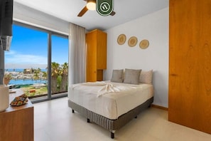 A bedroom with a large bed, a view of the sea, and a wooden cabinet. - New Listing 2BR condo near the ocean with pool, gym, WiFi, and parking. (Bahia de Banderas)