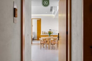 A modern kitchen with a dining area, wooden furniture, and a visible door leading to another room. - New Listing 2BR condo near the ocean with pool, gym, WiFi, and parking. (Bahia de Banderas)