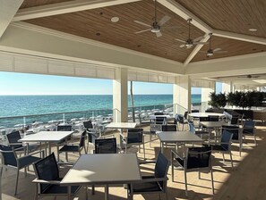 An outdoor seating area with tables and chairs, overlooking the sea. - Awesome Private Beach Club & Pool w/ shuttle. Cozy 3-bed Condo in Bonita Bay (Bonita Springs)