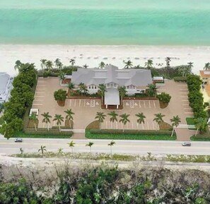 Ein Hotel mit Parkplatz, Blick auf den Strand und Palmen.