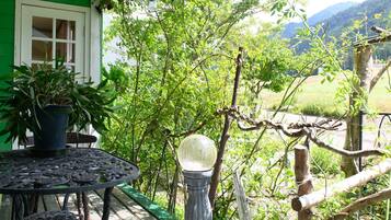 A patio with a table and chairs, surrounded by greenery and a view of the countryside.