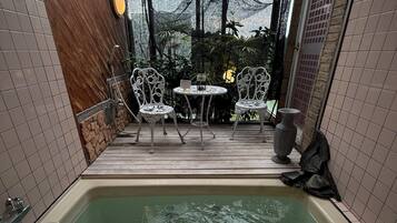Un área de spa con un jacuzzi, dos sillas metálicas blancas y una mesa.