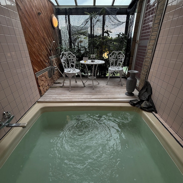 Un área de spa con un jacuzzi, dos sillas metálicas blancas y una mesa.