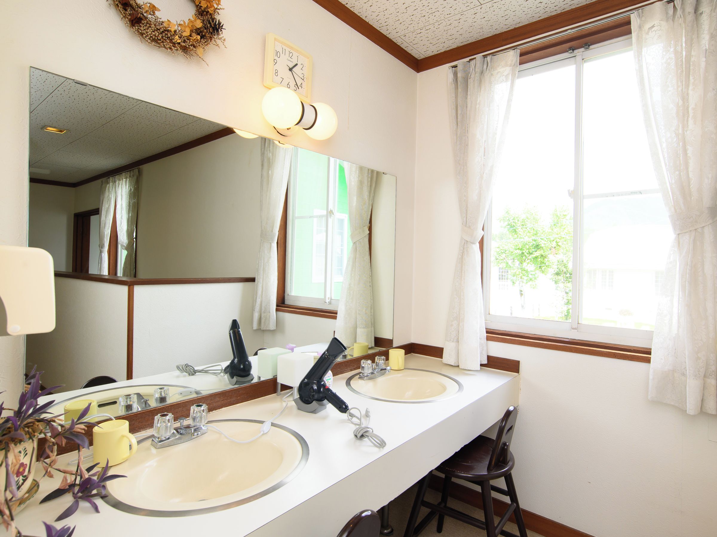 A bathroom with two sinks, a mirror, and a window with curtains.