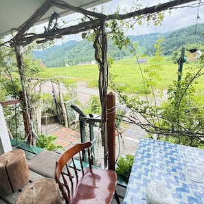 A covered outdoor seating area with a view of a green landscape. - Tateyama Foothill Onsen Crayon House (Toyama)