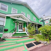 Un edificio verde con un porche, escalones y una estatua de un oso.