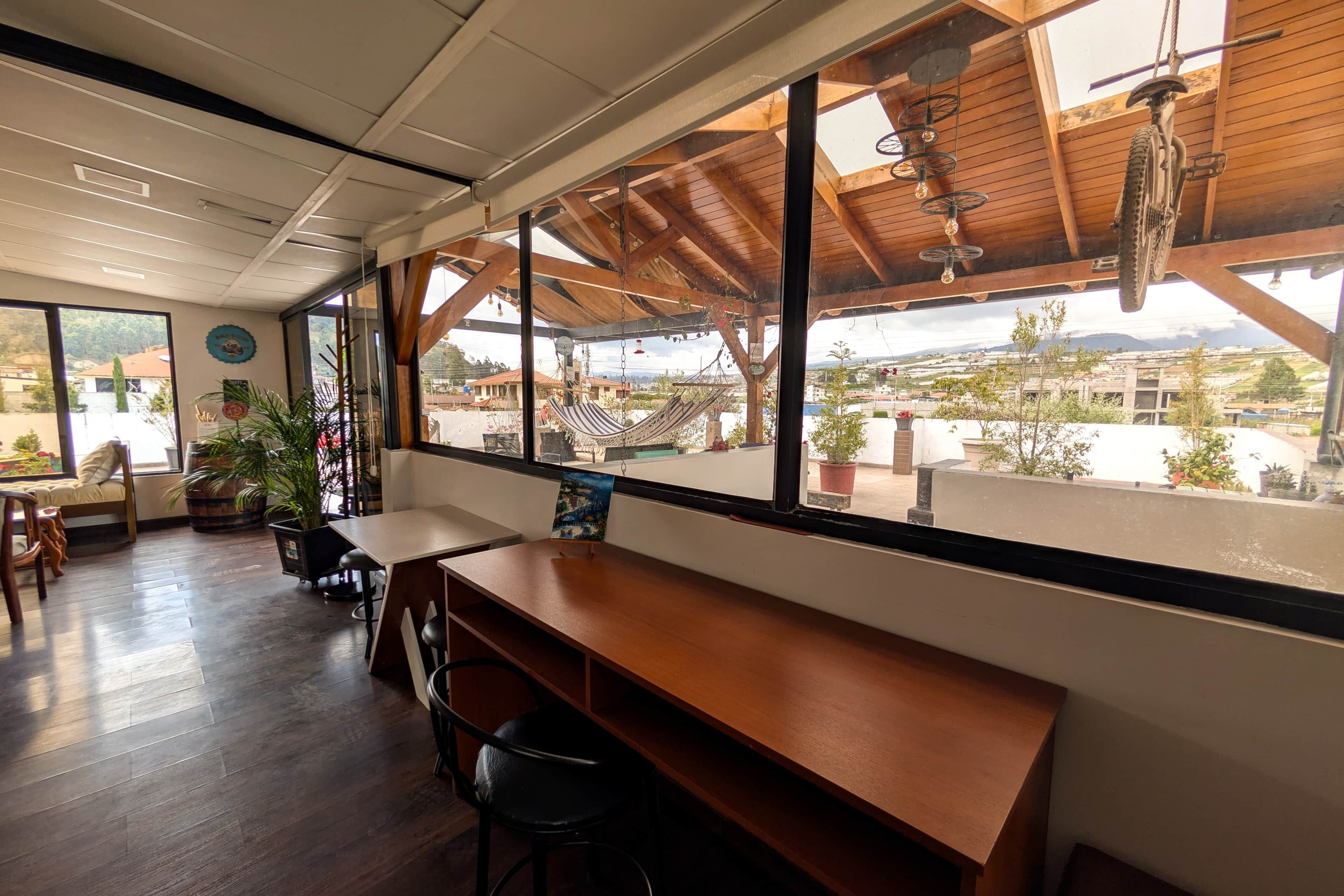 Um restaurante com decoração em madeira, amplas janelas e vista para a paisagem urbana.