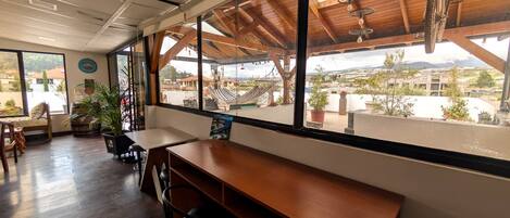 Un restaurante con interior de madera, grandes ventanales y vistas a la ciudad.