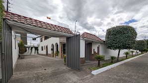 A residential property with a paved driveway, a covered entrance, and a small garden area with potted plants.