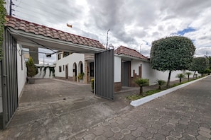 A residential property with a paved driveway, a covered entrance, and a small garden area with potted plants.