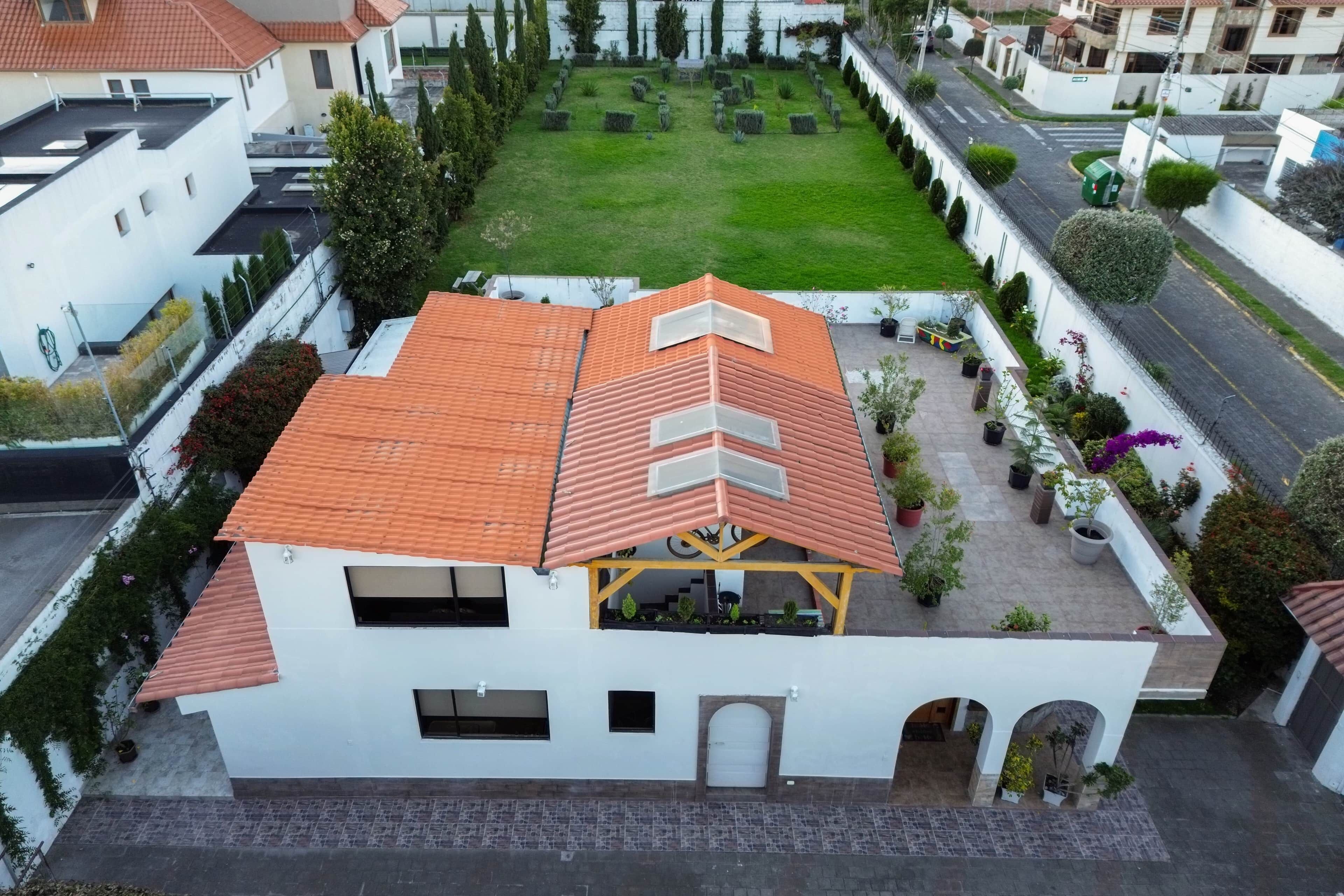 Ein modernes, zweistöckiges Gebäude mit roten Ziegeldach, einer überdachten Terrasse und einem gepflegten Garten.