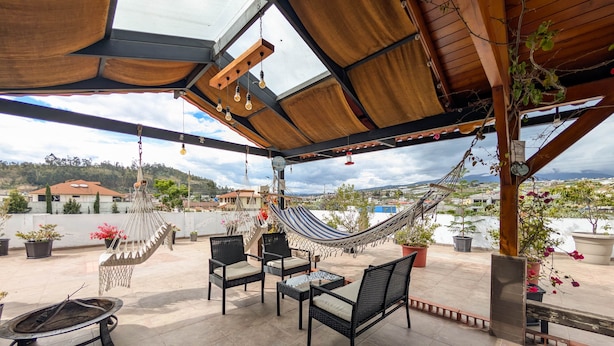 A rooftop patio with a hammock, chairs, and a table.