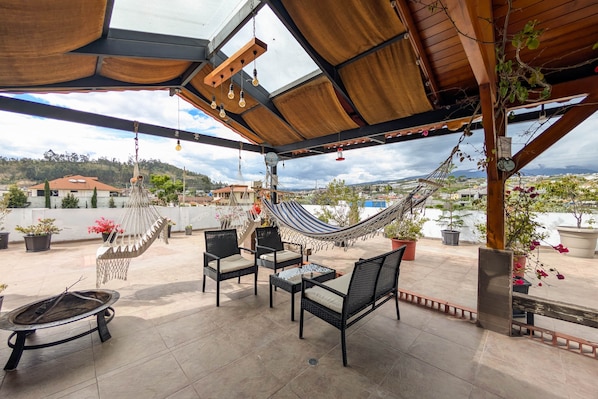 A rooftop patio with a hammock, chairs, and a table.