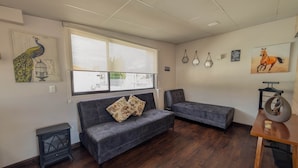 A living room with a grey sofa, a small table, and a window with a view.
